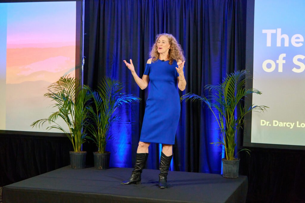 Dr. Darcy Lord speaking on stage during a speaker reel shoot in Sarasota