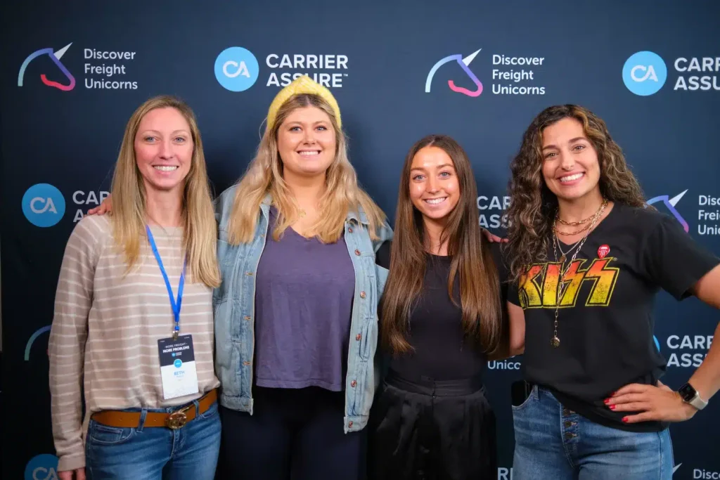 Group of event attendees pose for portrait photo in front of branded backdrop