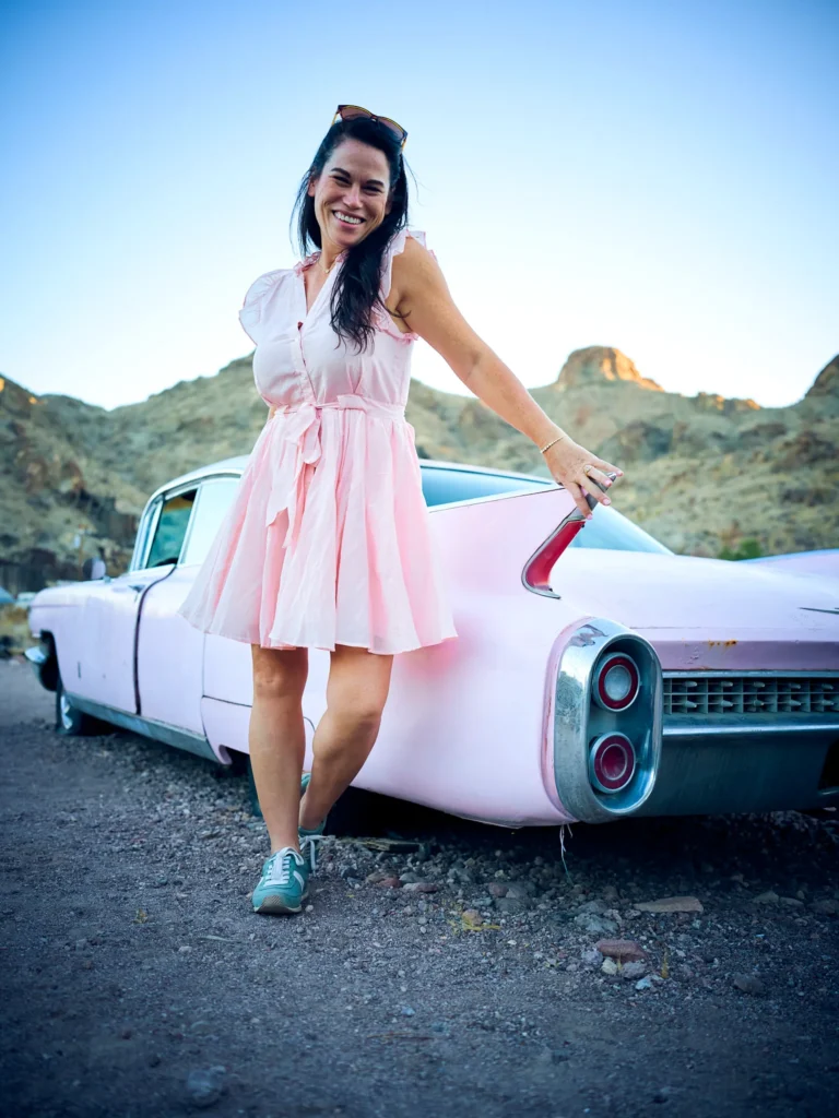 Fashion photography shoot of model in pink dress with a pink Cadillac in the desert