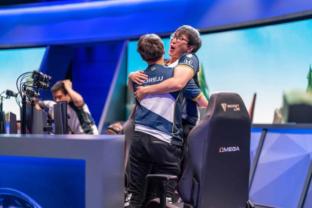 Photograph of teammates sharing a hug during celebratory moment at live gaming event - League of Legents