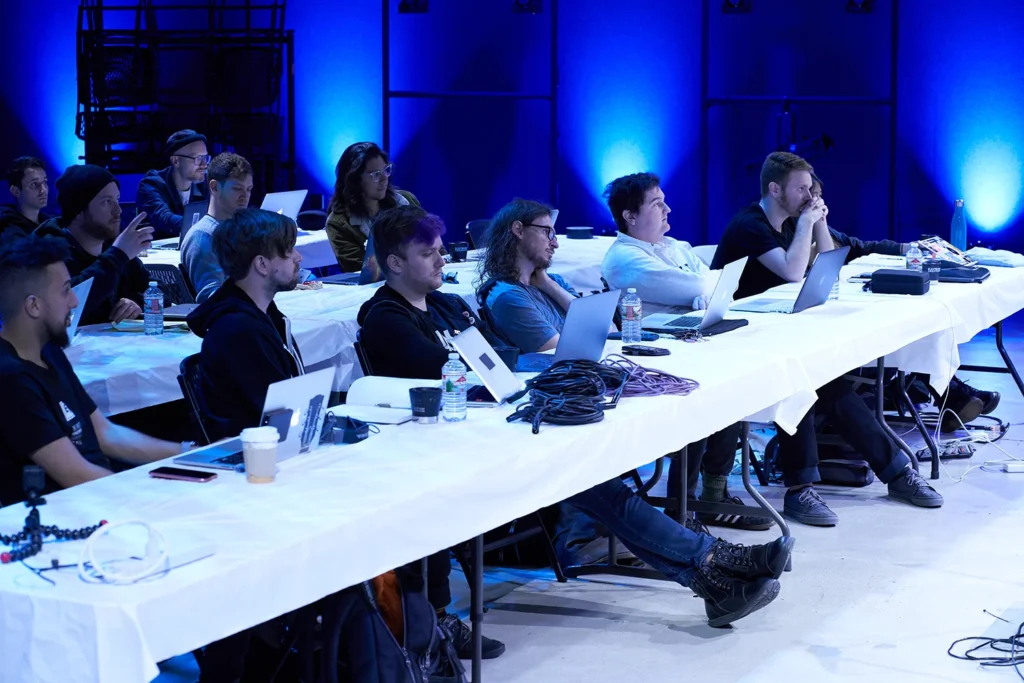 Photograph of live music conference attendees sitting in front of computers
