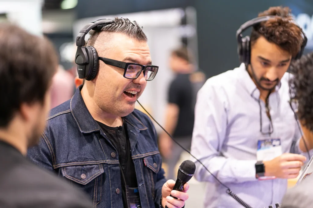 Photo at event of man talking and testing microphones at music tradeshow