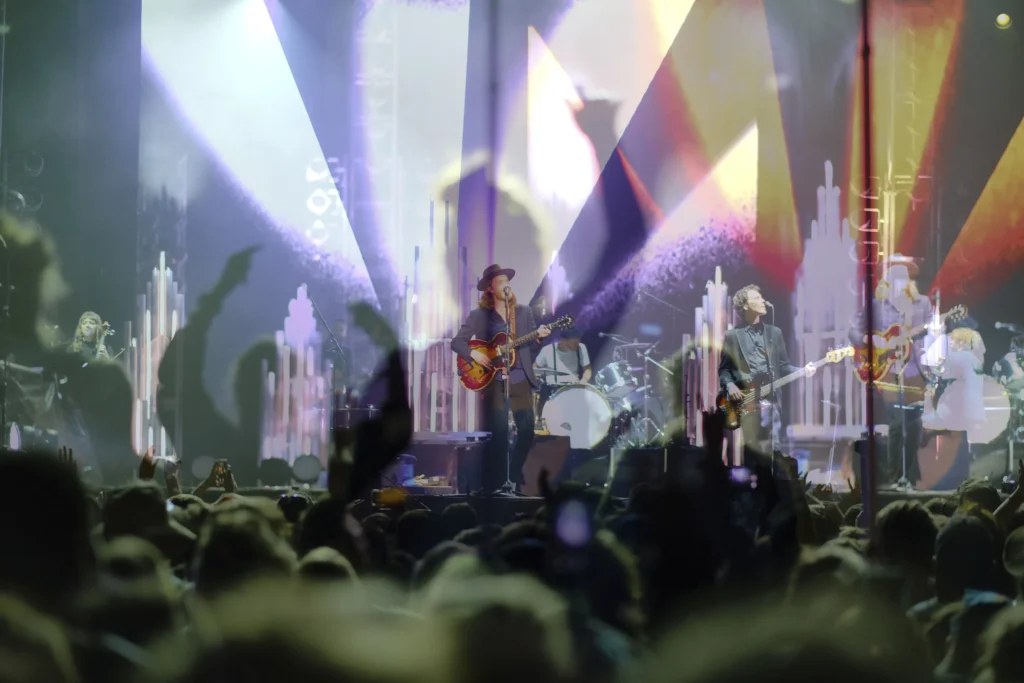 Creative live music concert photograph of Lumineers on stage with silhouettes of fans cheering over light projections