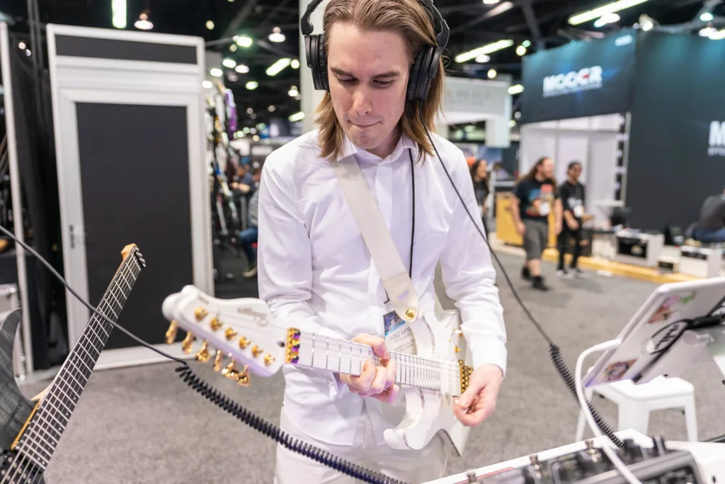 Portrait of man playing guitar and instruments at NAMM music tradeshow