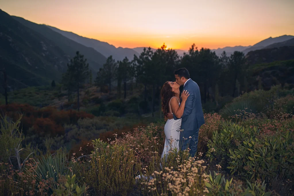 Bride and groom photographed during romantic kiss at sunset