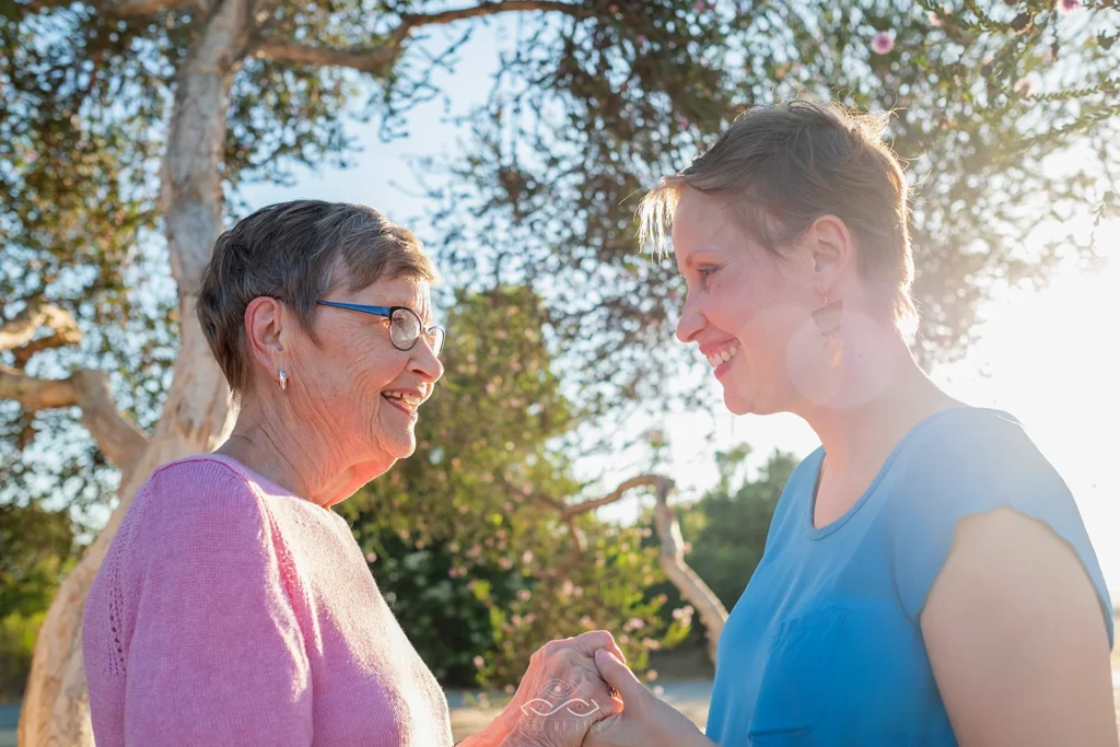 Mother and daughter family portrait session happy and smiling outside with the sun shining through