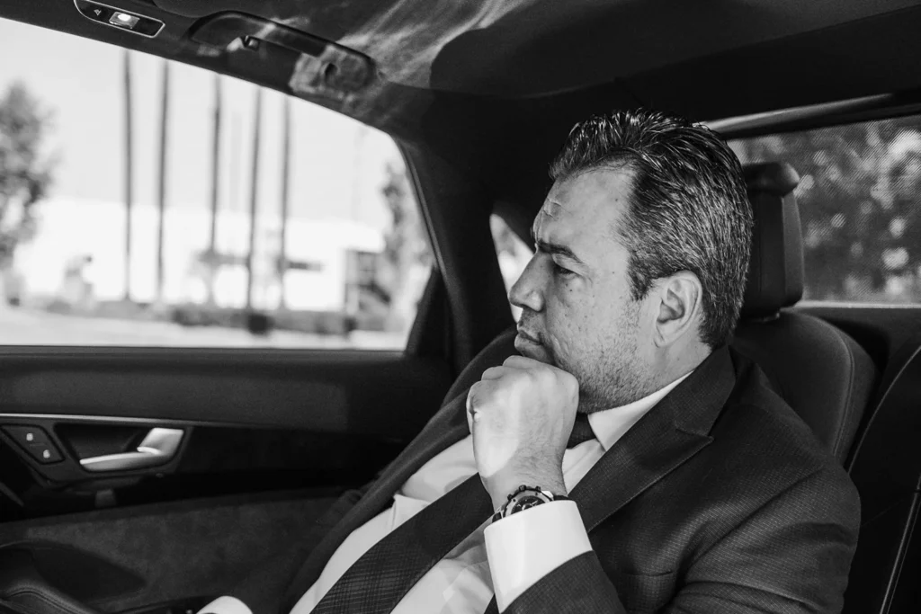 Portrait photography of distinguished man in suit sitting in car in black and white