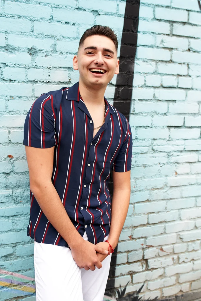 Professional photographer headshot portrait in environment of young man smiling and laughing in urban environment