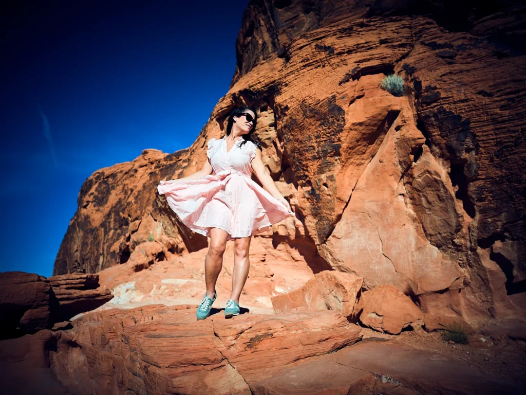 Fashion photography portrait shoot of model in pink dress against red rocks mountains
